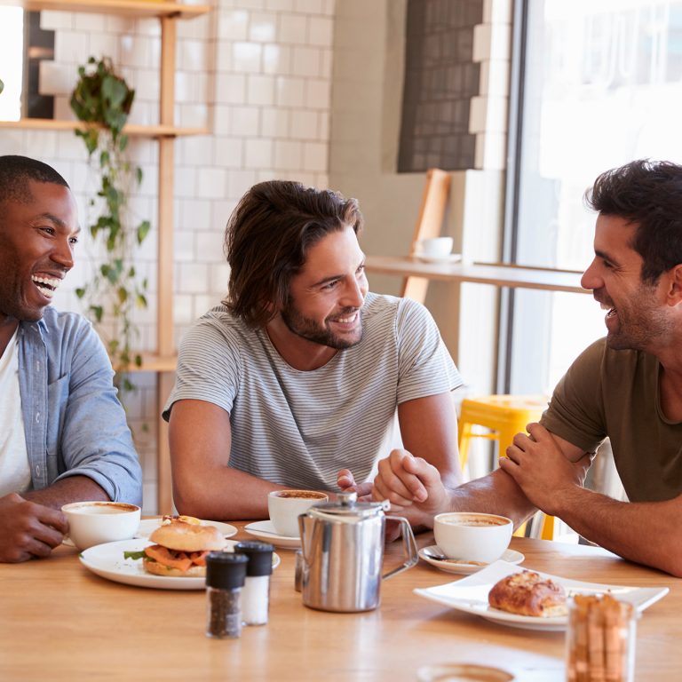 Three Male Friends Meeting For Lunch In Coffee Shop