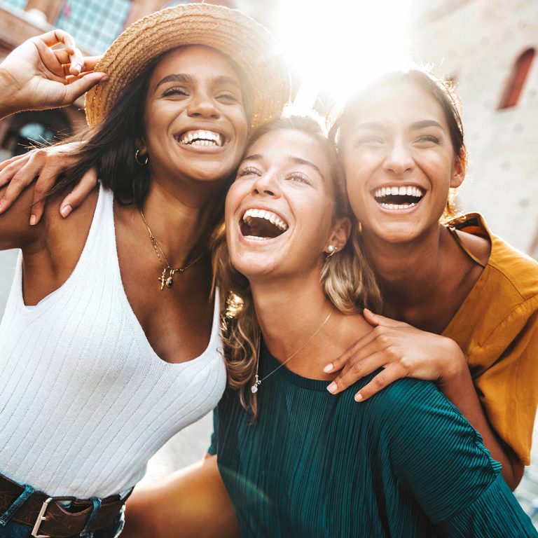 Three multiracial young women having fun walking on city street - Happy girlfriends hanging outside on a sunny day - Different females laughing together outside - Life style and friendship concept
